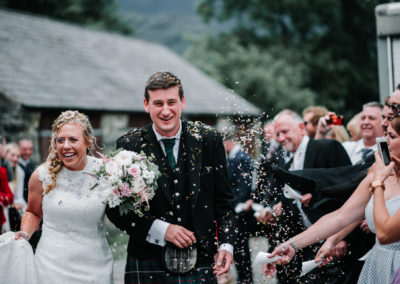 Bride and groom walking through confetti at Llyn Gwynant Campsite